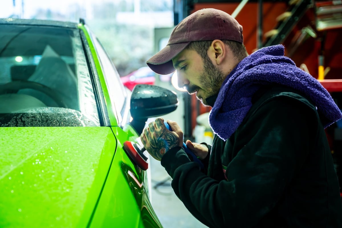 Technician polishing a vibrant vehicle to a flawless glossy finish